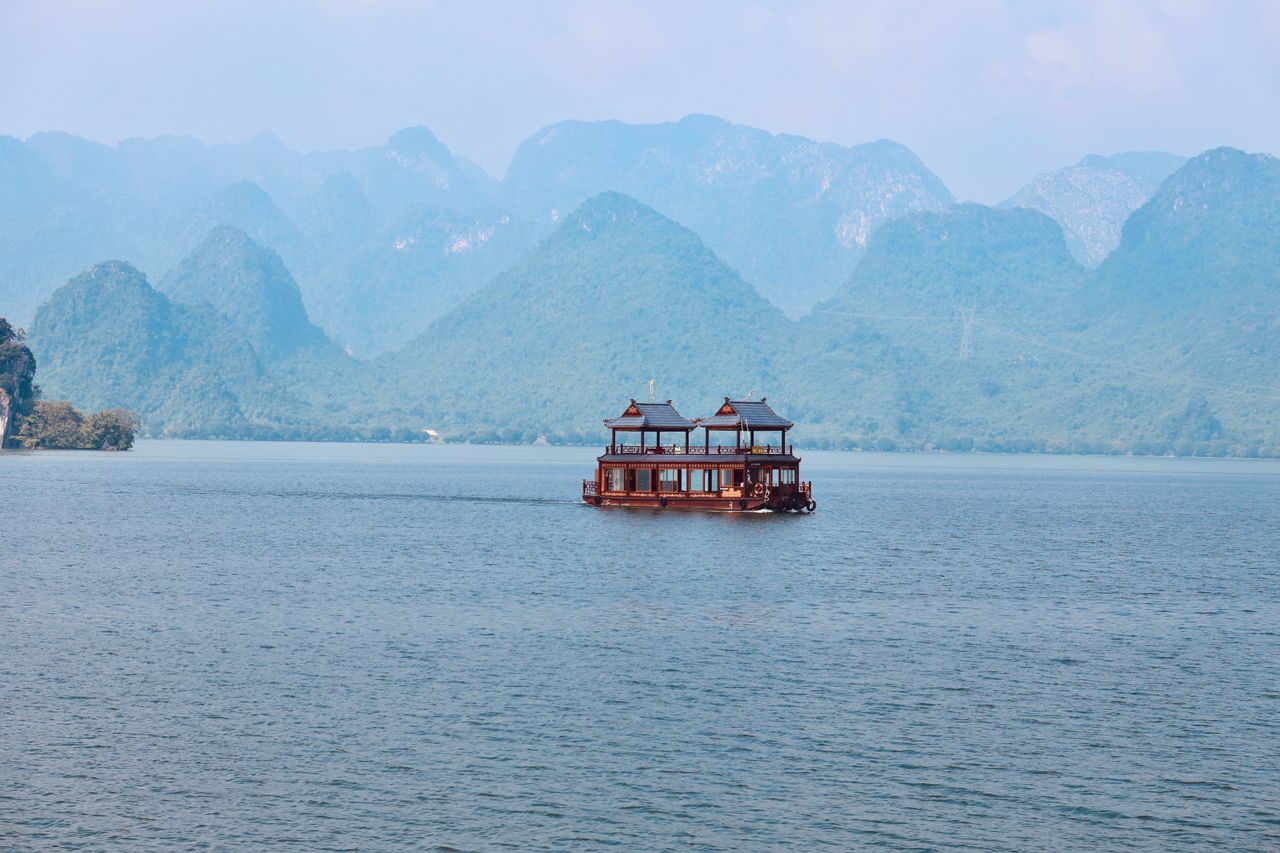 Traditional houseboat on tranquil Tam Chúc Lake against karst mountains in Hà Nam, Vietnam.